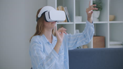 Young-cheerful-woman-wearing-virtual-reality-headset-watching-360-VR-video-movie-sitting-in-the-bed-at-home.-Portrait-Of-Young-Woman-In-Virtual-Reality-Glasses-Sitting-On-The-Sofa-At-Home